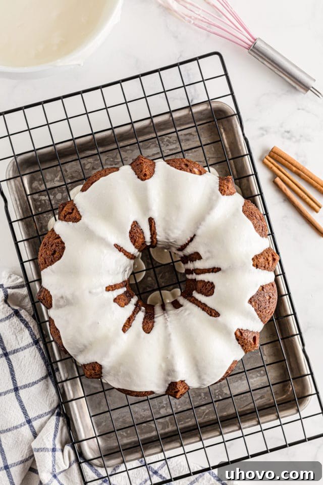 A freshly glazed Cinnamon Roll Cake resting on a wire cooling rack, with the glaze beautifully drizzled over its surface.