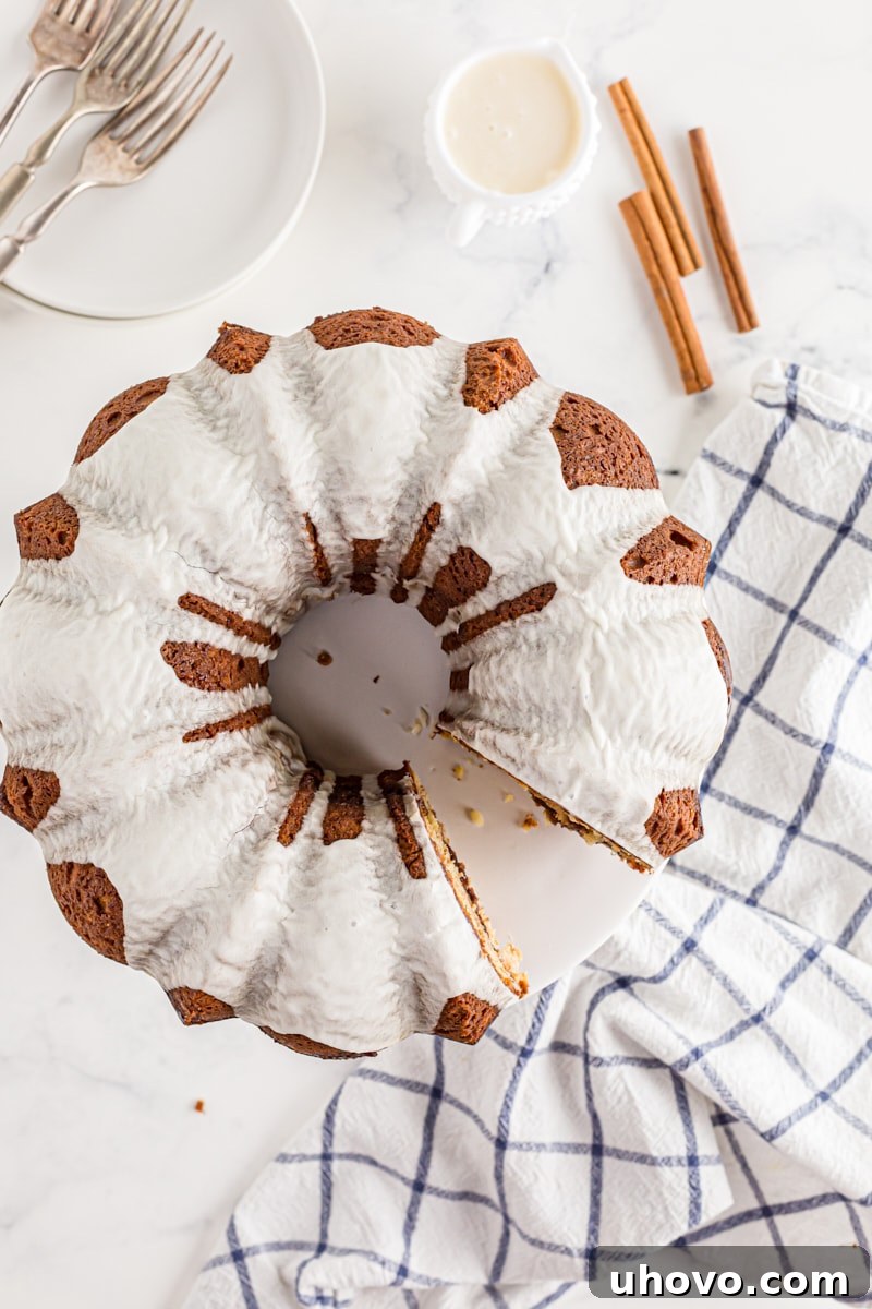A beautifully glazed Cinnamon Roll Cake resting on a kitchen counter, with one slice already removed, showcasing its delicious interior.