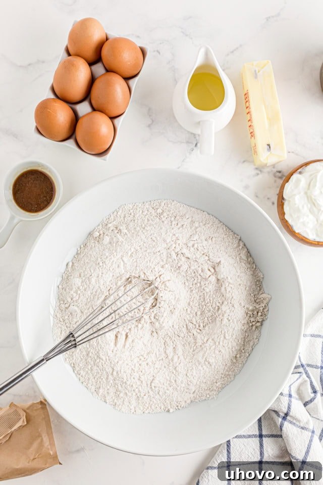 The dry ingredients for Cinnamon Roll Cake being meticulously whisked together in a large mixing bowl.
