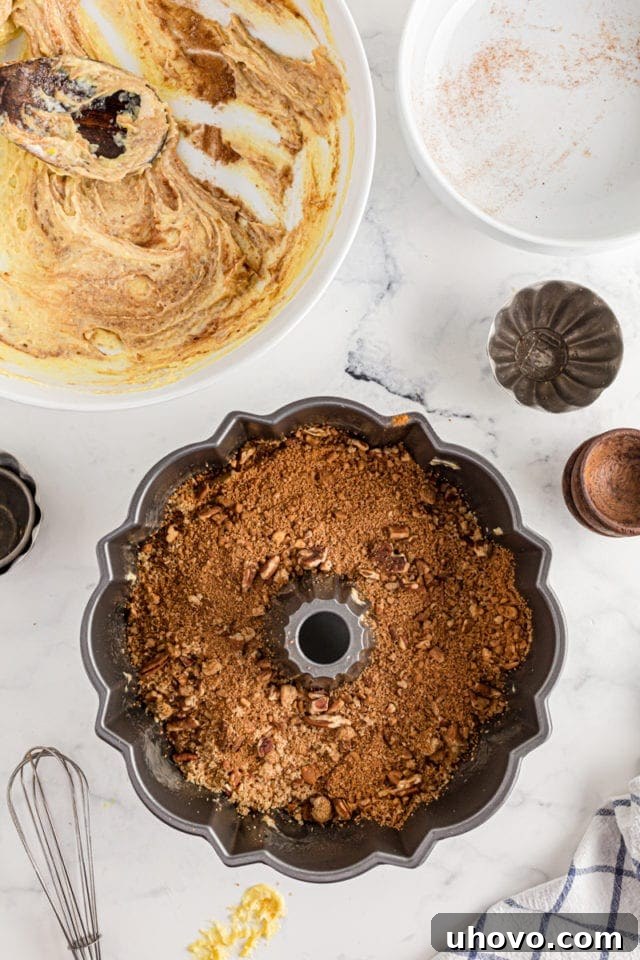 The first layer of Cinnamon Roll Cake batter neatly spread in a Bundt pan, topped with the cinnamon filling.