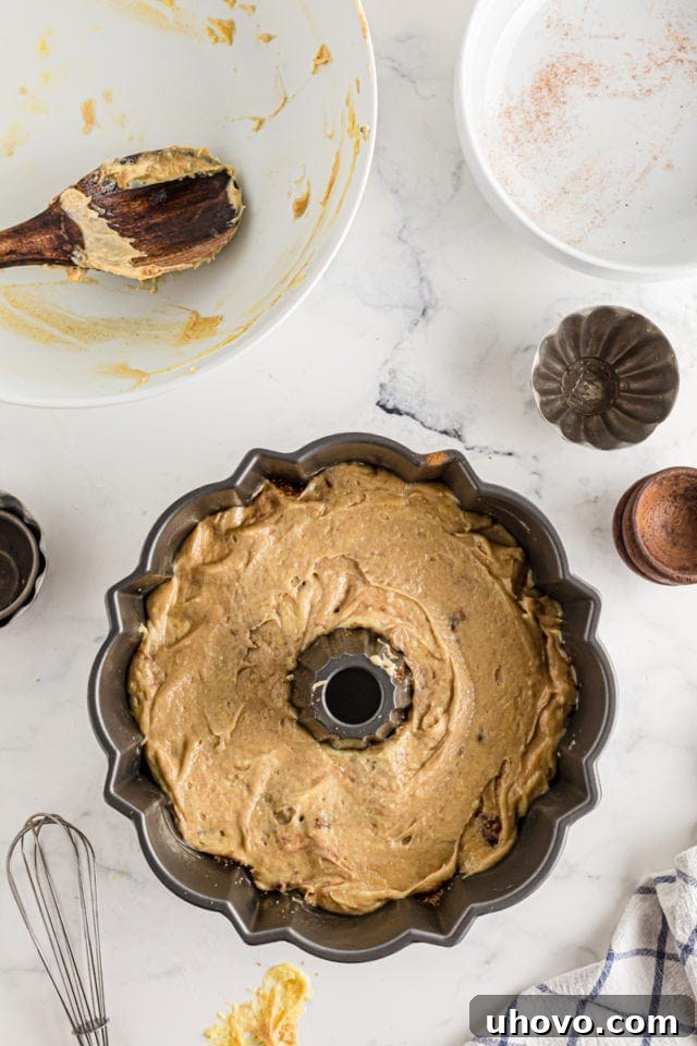 The second and final layer of cake batter being carefully smoothed over the cinnamon filling in a Cinnamon Roll Cake.