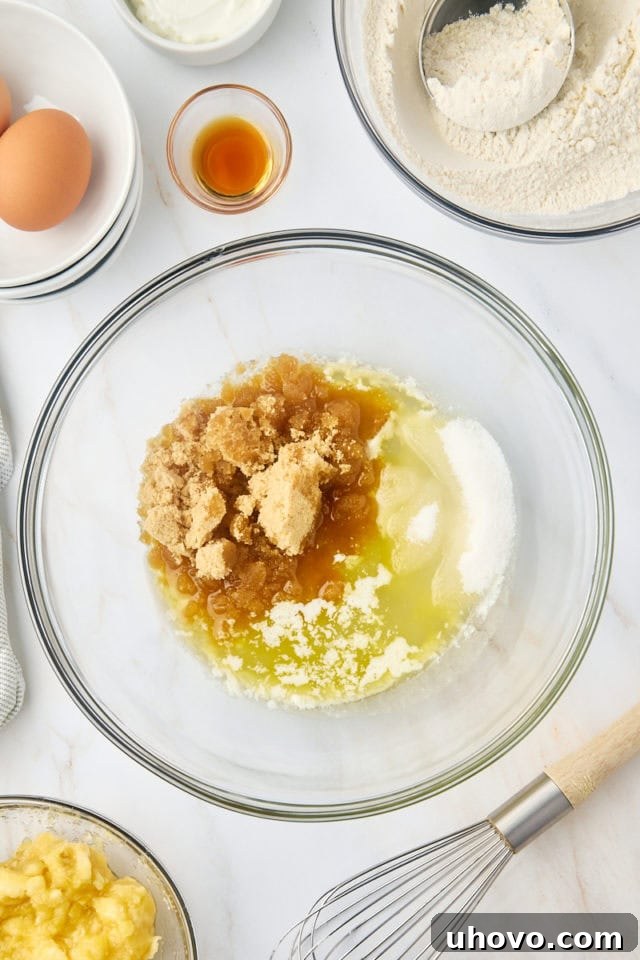 overhead view of melted butter, vegetable oil, brown sugar, and sugar in a glass mixing bowl