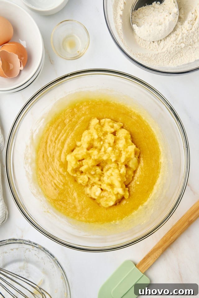 overhead view of mashed bananas added to quick bread batter