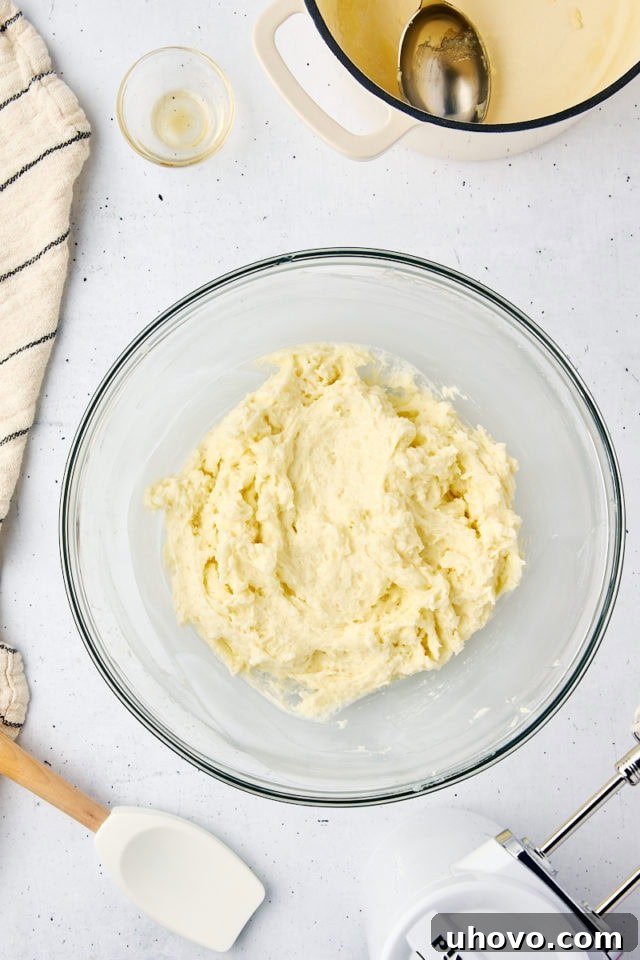 Overhead view of the finished ermine frosting, light, fluffy, and silky smooth, in a glass mixing bowl, ready to be applied.