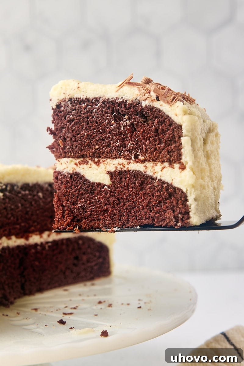 A slice of mahogany cake being carefully lifted from the main cake using a cake server, highlighting its perfect layers and smooth frosting.