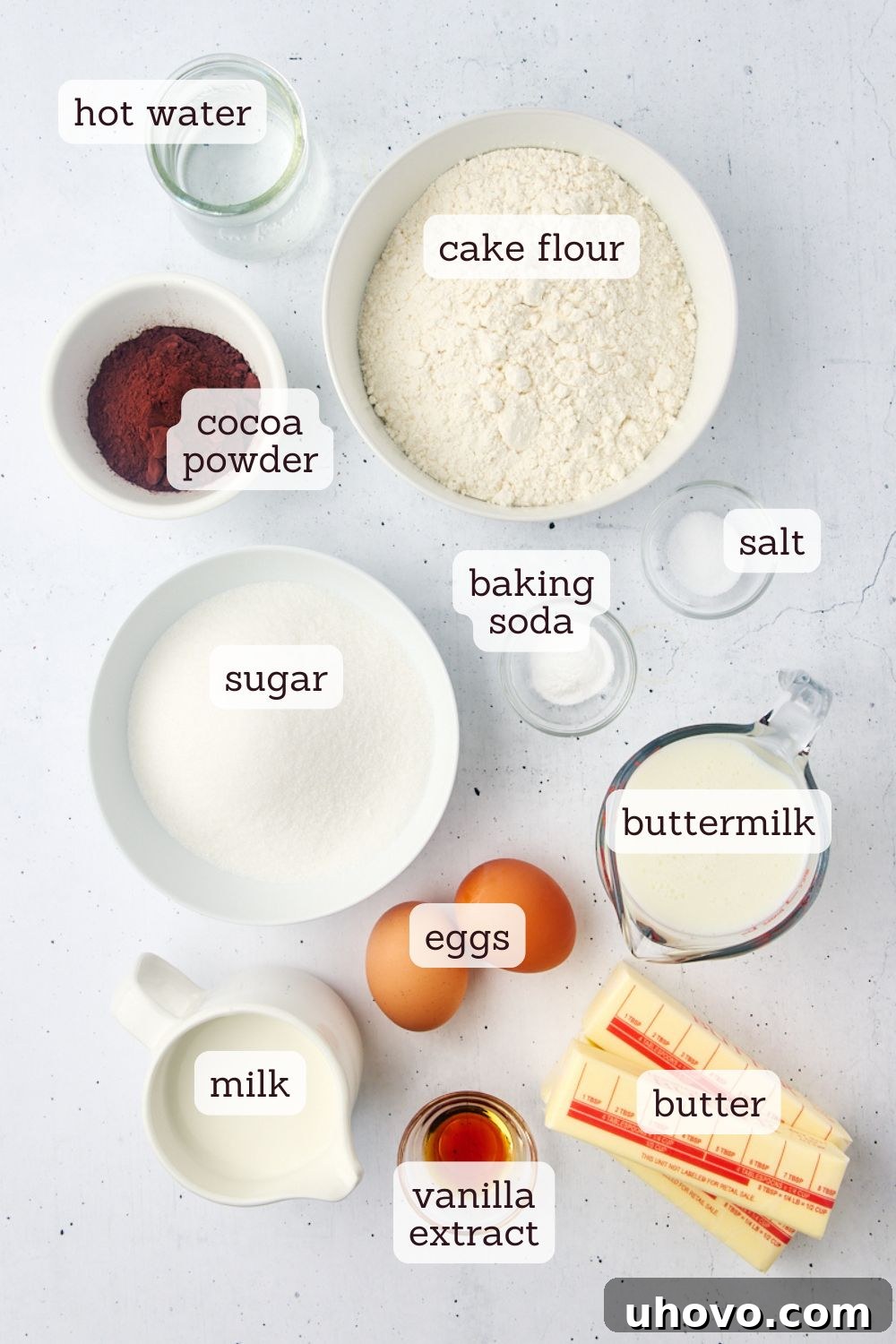 Overhead view of various dry and wet ingredients carefully laid out for making a mahogany cake, including flour, cocoa, butter, and eggs.