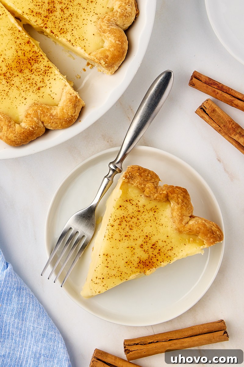 An overhead view of a slice of sugar cream pie on a white plate, placed neatly beside the rest of the pie in its baking dish, ready to be enjoyed.