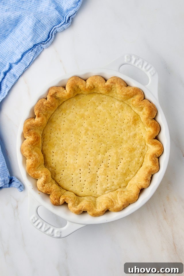 An overhead shot of a golden-brown, perfectly pre-baked pie crust waiting to be filled.