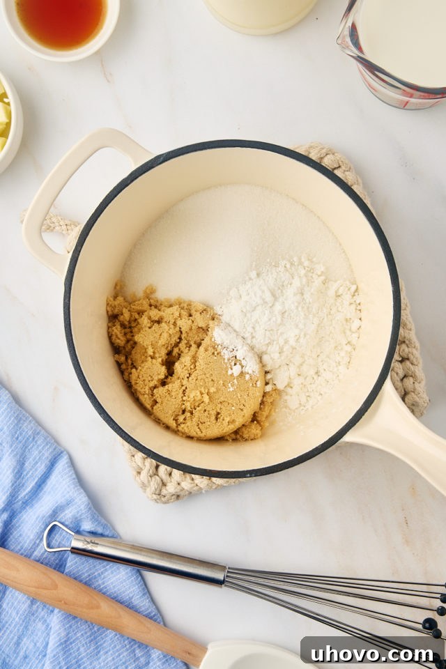 An overhead view of granulated sugar, brown sugar, and cornstarch expertly mixed in a saucepan, ready for the liquid ingredients.