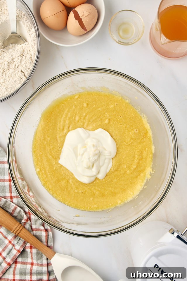 overhead view of sour cream added to apple cider donut cake batter