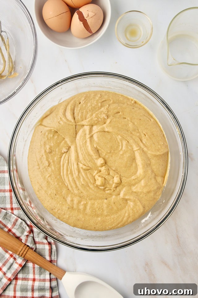 overhead view of mixed apple cider donut cake batter in a glass mixing bowl