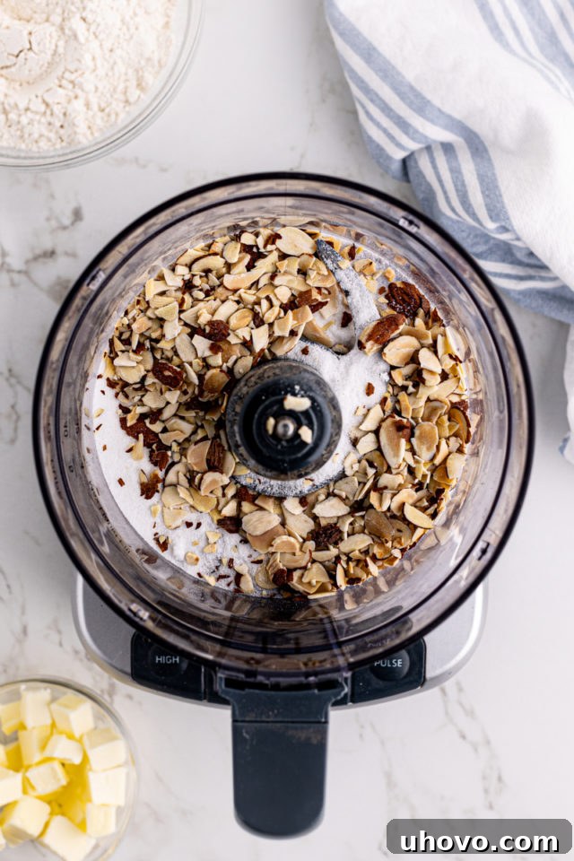 Overhead view of almonds and sugar in food processor bowl