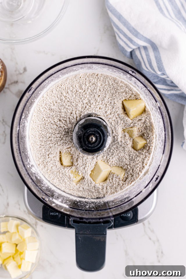 Overhead view of butter added to crumb mixture in food processor