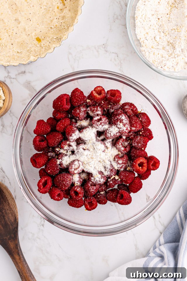 Overhead view of dry ingredients added to raspberries in bowl