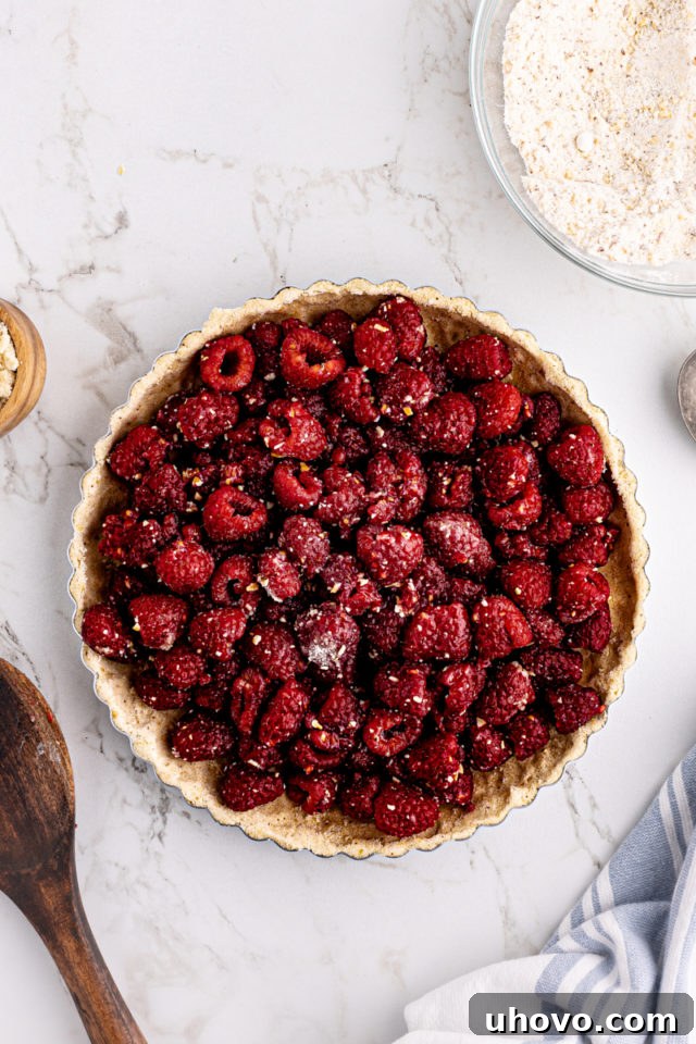Overhead view of raspberries added to almond tart crust