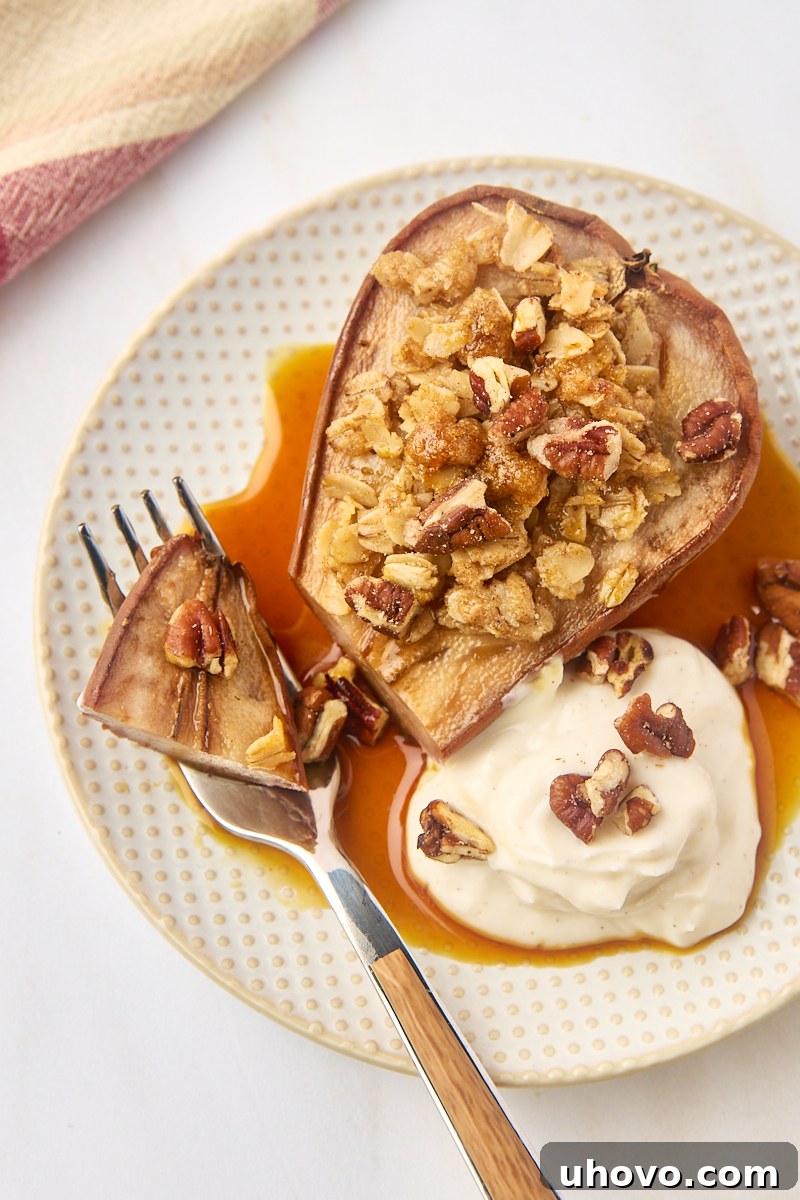 A delectable close-up shot of a baked pear on a plate, with a fork gently taking a perfect bite, showcasing the tender fruit and crunchy oat topping.