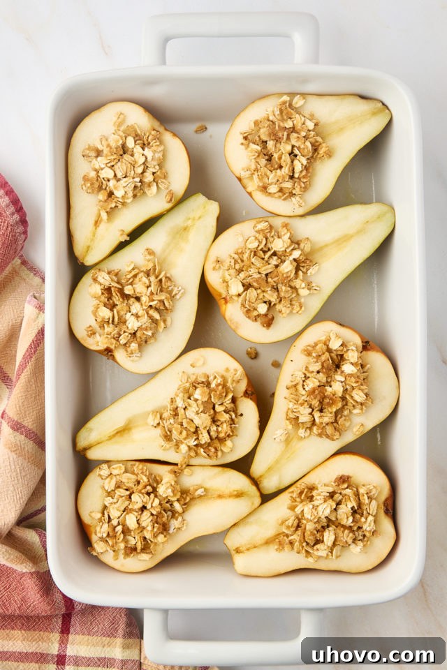 A visual of pear halves meticulously filled with the spiced oat mixture, nestled in a baking dish and ready to be placed into the oven.