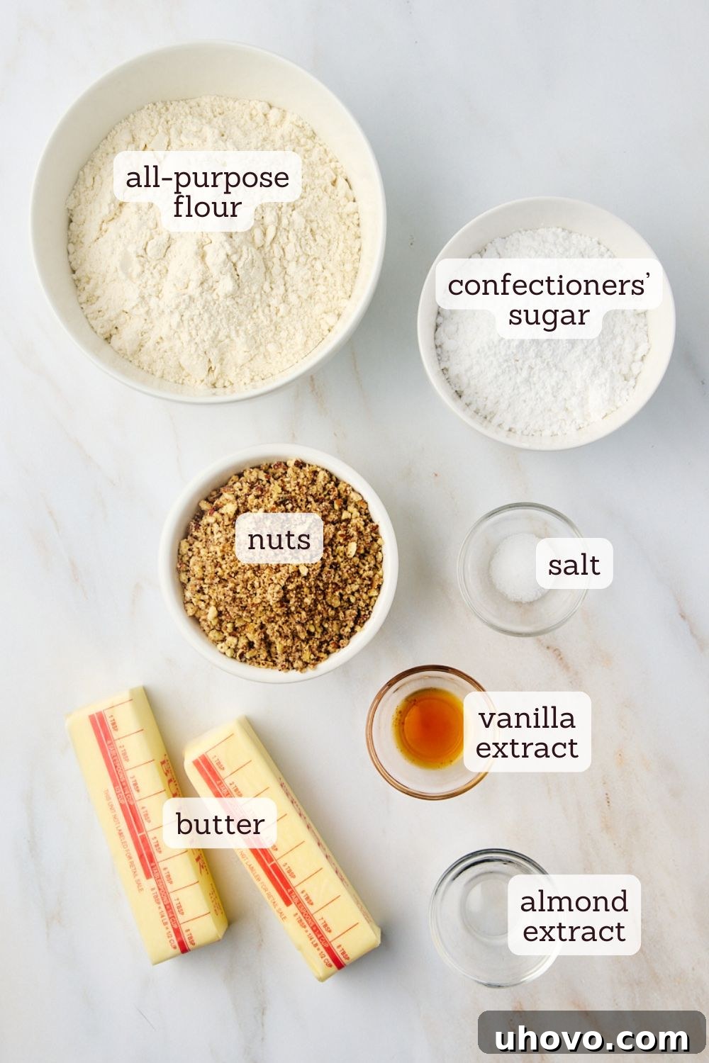 Overhead view of various high-quality ingredients, including flour, sugar, butter, and nuts, neatly arranged for baking classic snowball cookies.