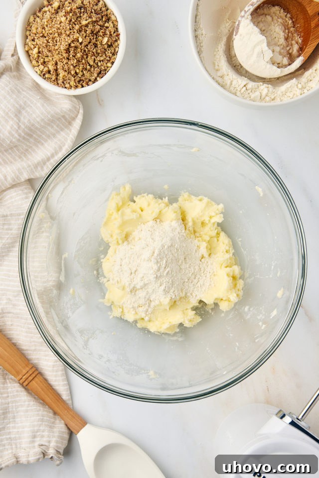 Finely ground toasted nuts being gently folded into the creamed butter and sugar mixture.