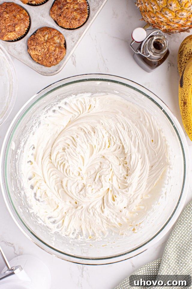 Overhead view of perfectly whipped, fluffy cream cheese frosting in a mixing bowl, ready for piping.