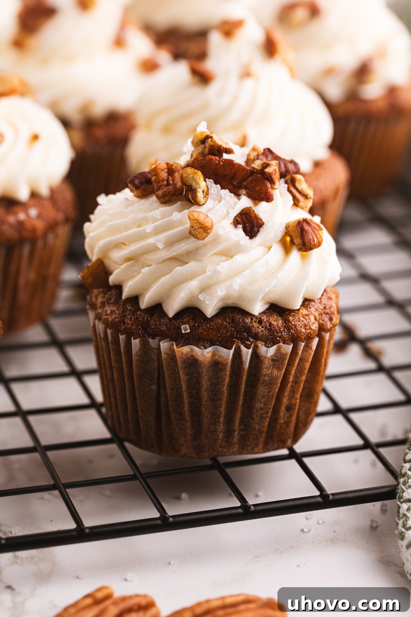 A beautifully frosted Hummingbird Cupcake with cream cheese frosting, resting on a wire rack.