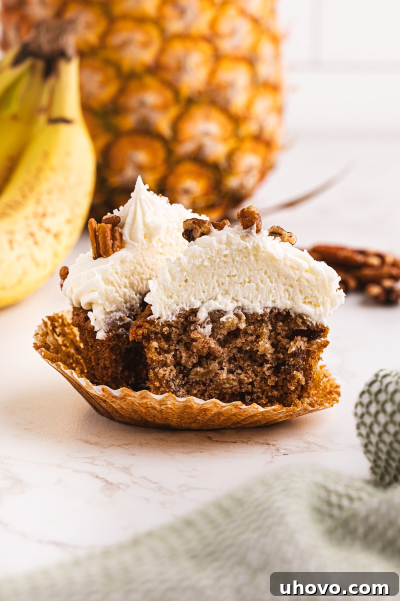 A Hummingbird Cupcake sliced in half to reveal its moist texture, studded with banana and pineapple pieces.