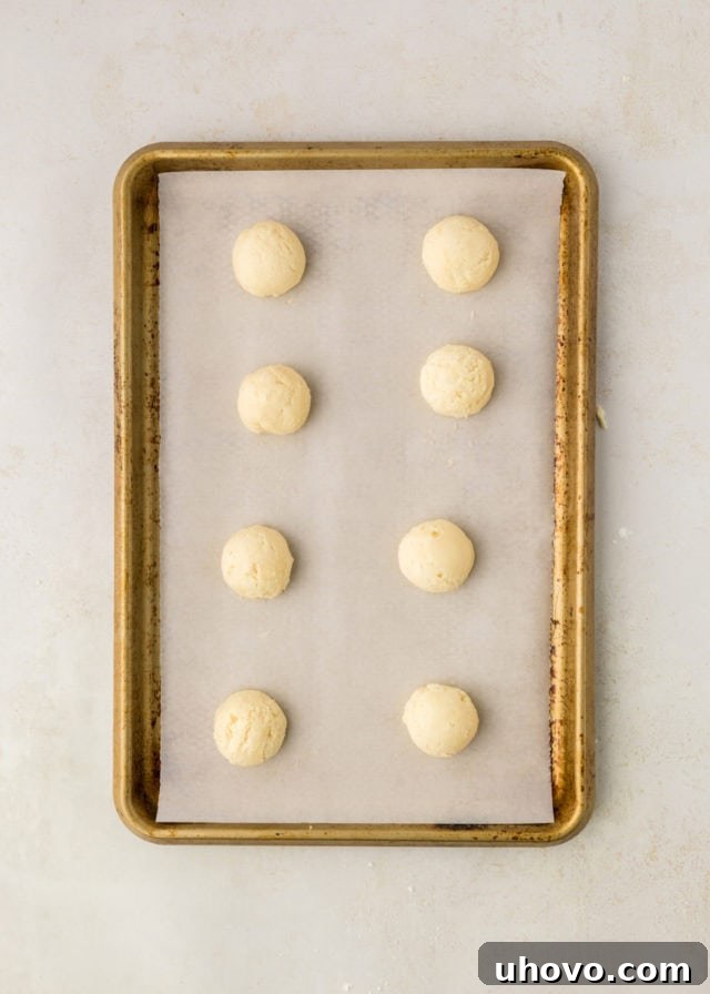 Overhead view of uniformly rolled peppermint meltaway cookie dough balls arranged on a baking sheet, ready for the oven.