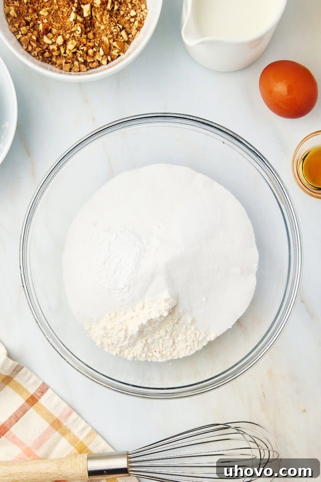 overhead view of sugar, flour, baking powder, and salt in a glass mixing bowl