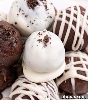 Several Oreo truffles on a white plate, showcasing various chocolate coatings and toppings.