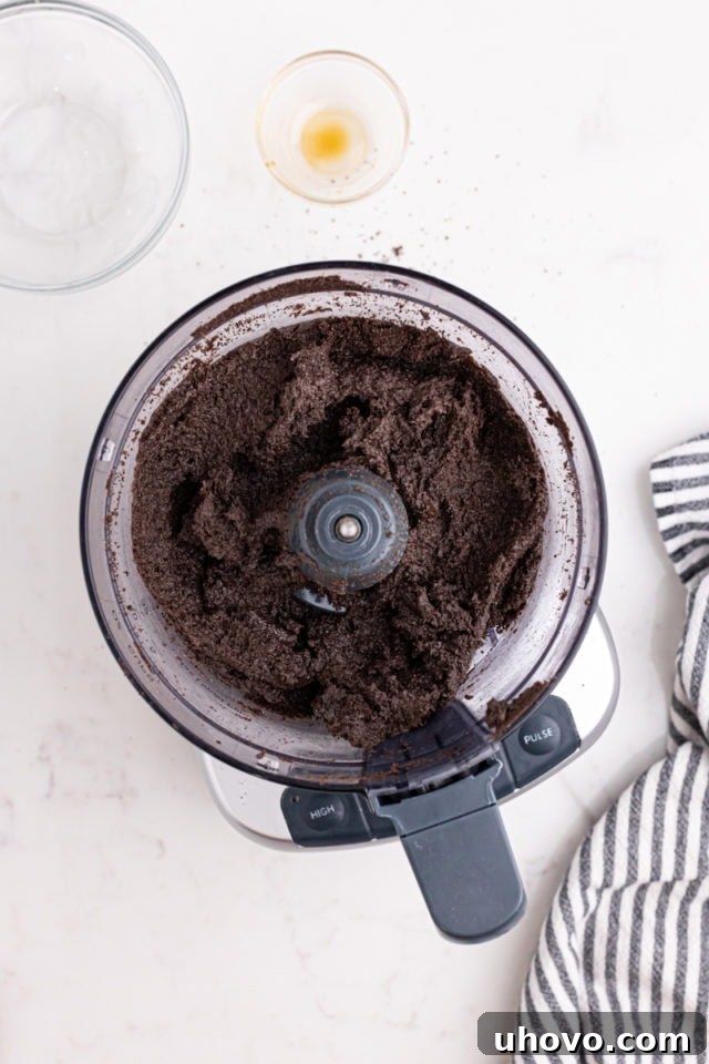 Overhead view of the combined Oreo truffle mixture in the bowl of a food processor, showing a cohesive, dough-like consistency.