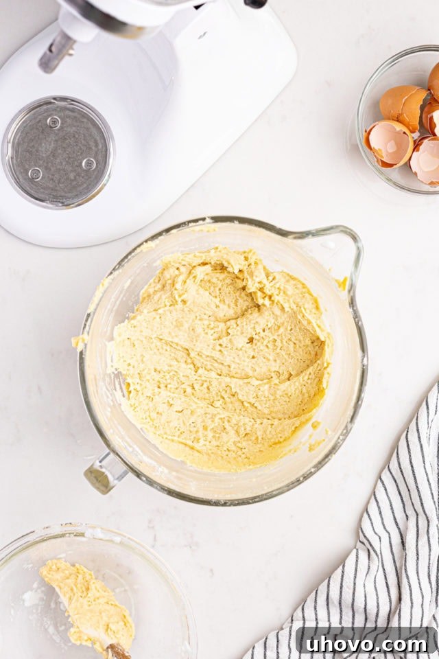 Overhead view of mixed Italian rainbow cookie dough in a glass mixing bowl, showcasing its smooth texture.