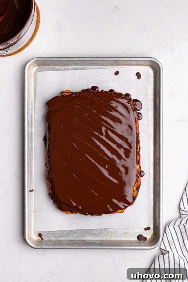 Overhead view of the Italian rainbow cookies flipped over, and melted dark chocolate being spread on the second side.