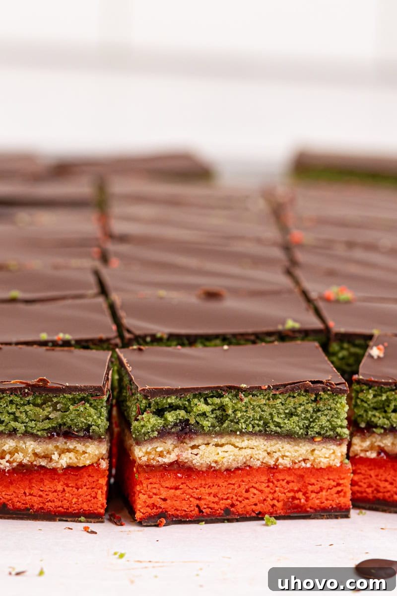 Several vibrant Italian rainbow cookies neatly arranged on parchment paper.