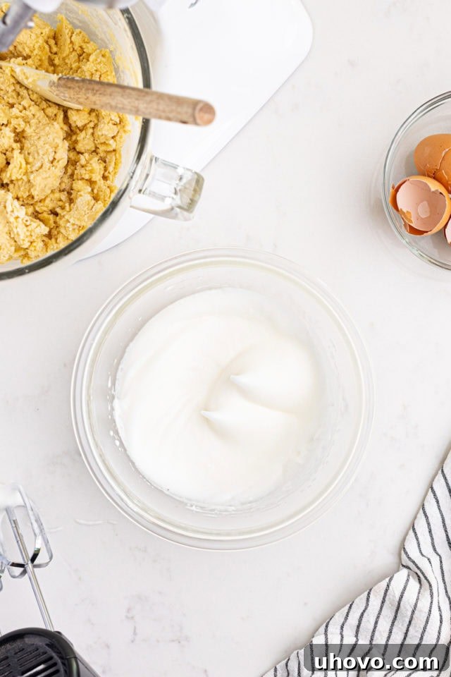Overhead view of egg whites whipped to stiff peaks in a separate mixing bowl.