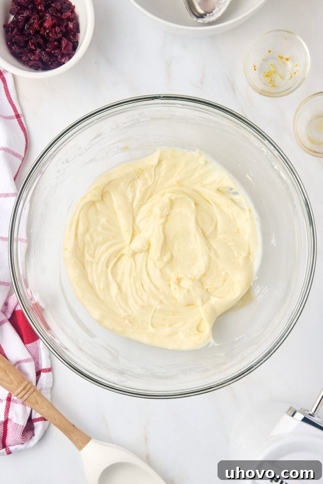 Overhead view of orange cream cheese frosting in a mixing bowl