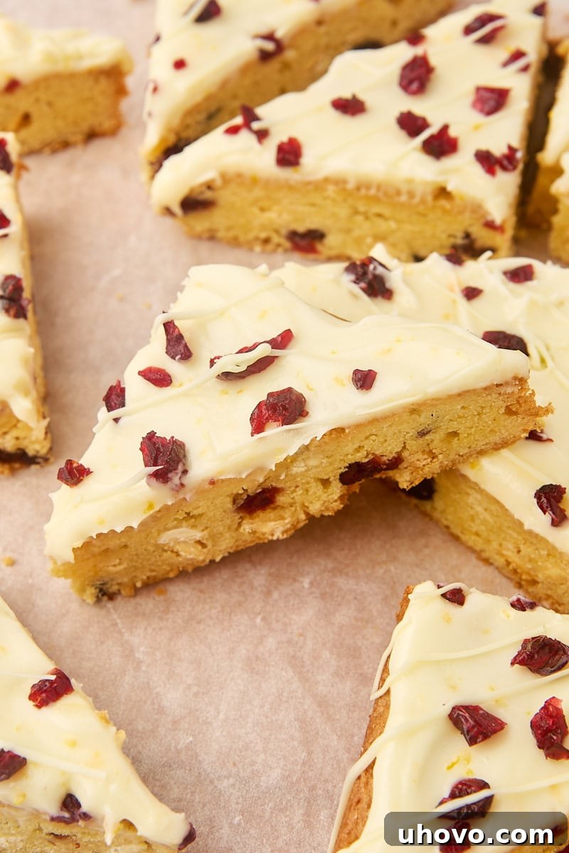 Several cranberry bliss bars on a parchment-covered cutting board