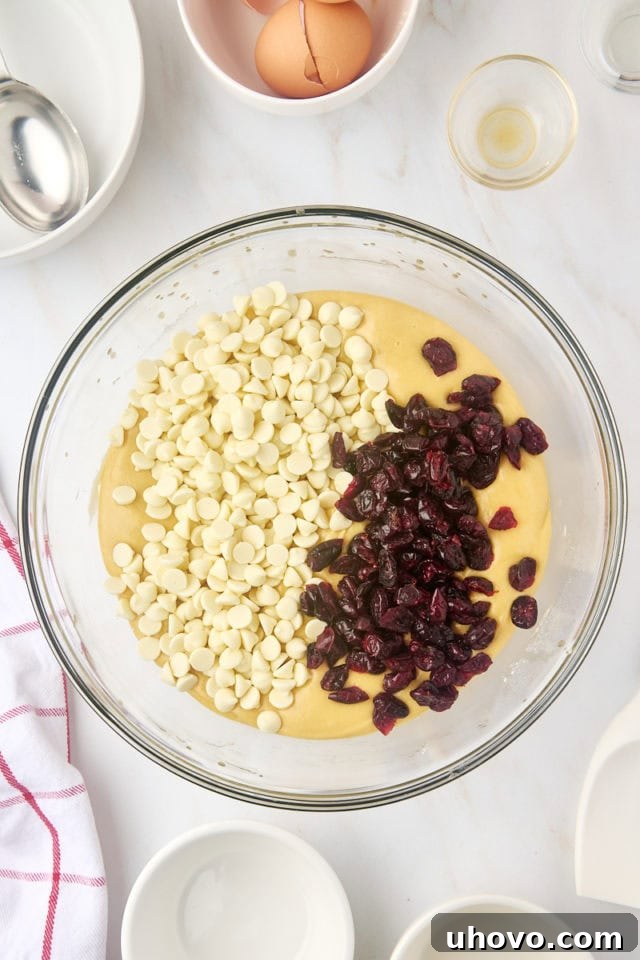 Overhead view of white chocolate chips and dried cranberries added to cranberry bliss bar batter