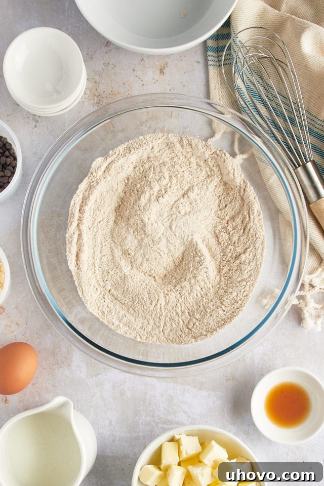 Overhead view of flour, sugar, baking powder, baking soda, and salt mixed in a large bowl.