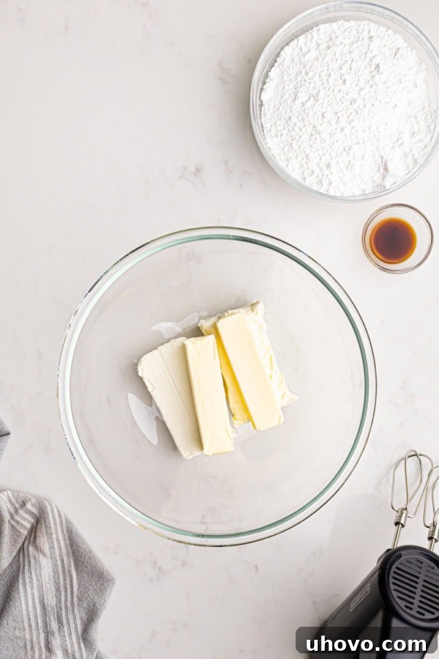 Overhead view of softened butter and cream cheese in a mixing bowl, ready to be beaten for cream cheese frosting.