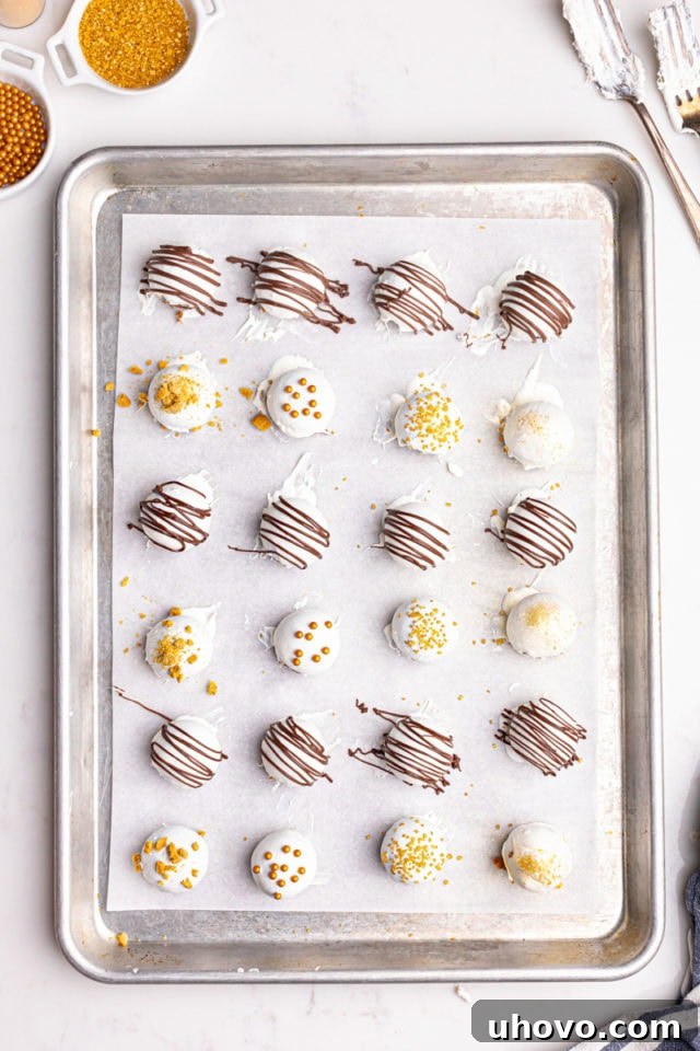 Overhead view of freshly-dipped gingerbread truffles, some adorned with festive sprinkles, neatly placed on a baking sheet, ready for setting.