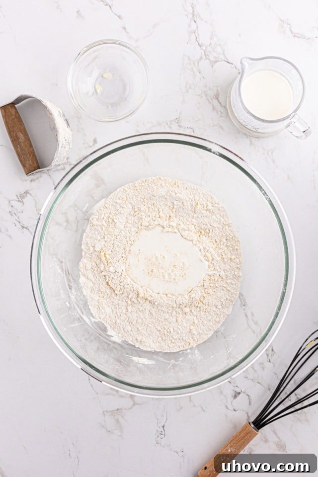 Overhead view of buttermilk poured into dry ingredients for biscuits
