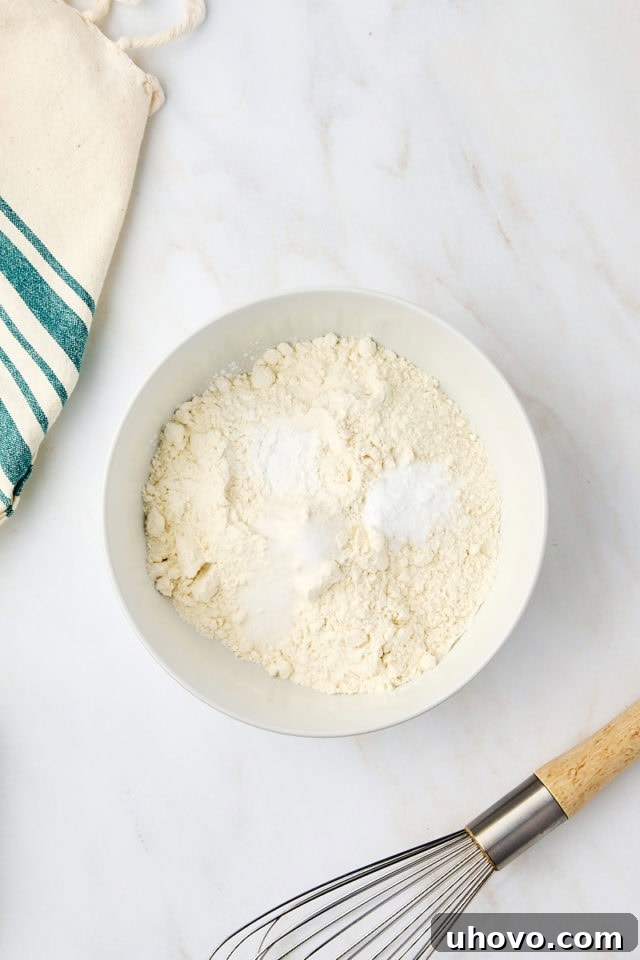 overhead view of flour, baking powder, baking soda, and salt in a white bowl