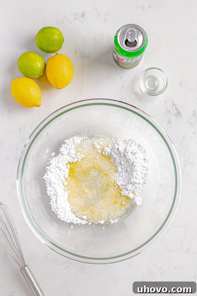 Overhead view of confectioners' sugar, 7UP, lemon juice, and vanilla extract combined in a glass bowl for the glaze.