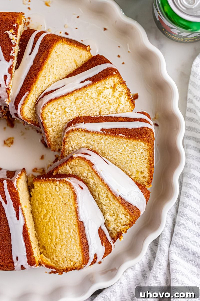 Overhead view of a perfectly sliced 7UP cake on a pristine white cake plate, revealing its moist texture.
