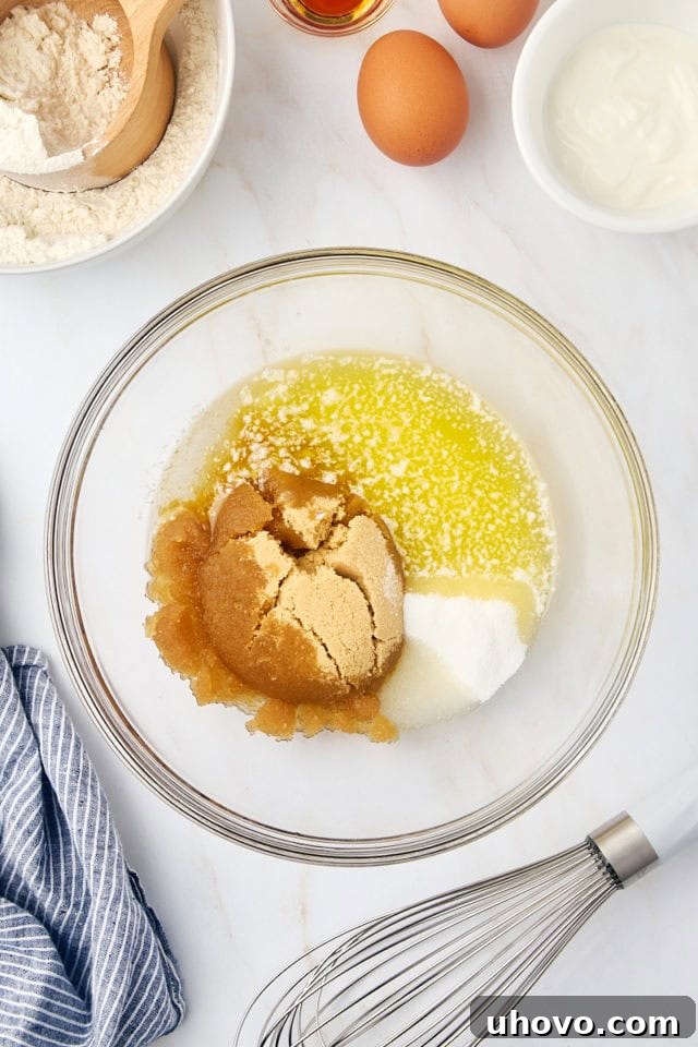overhead view of melted butter, oil, brown sugar, and sugar in a glass mixing bowl