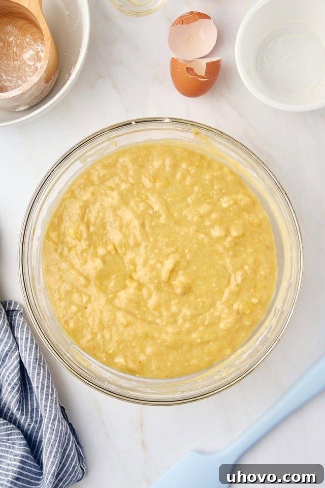 overhead view of banana bread batter in a glass mixing bowl
