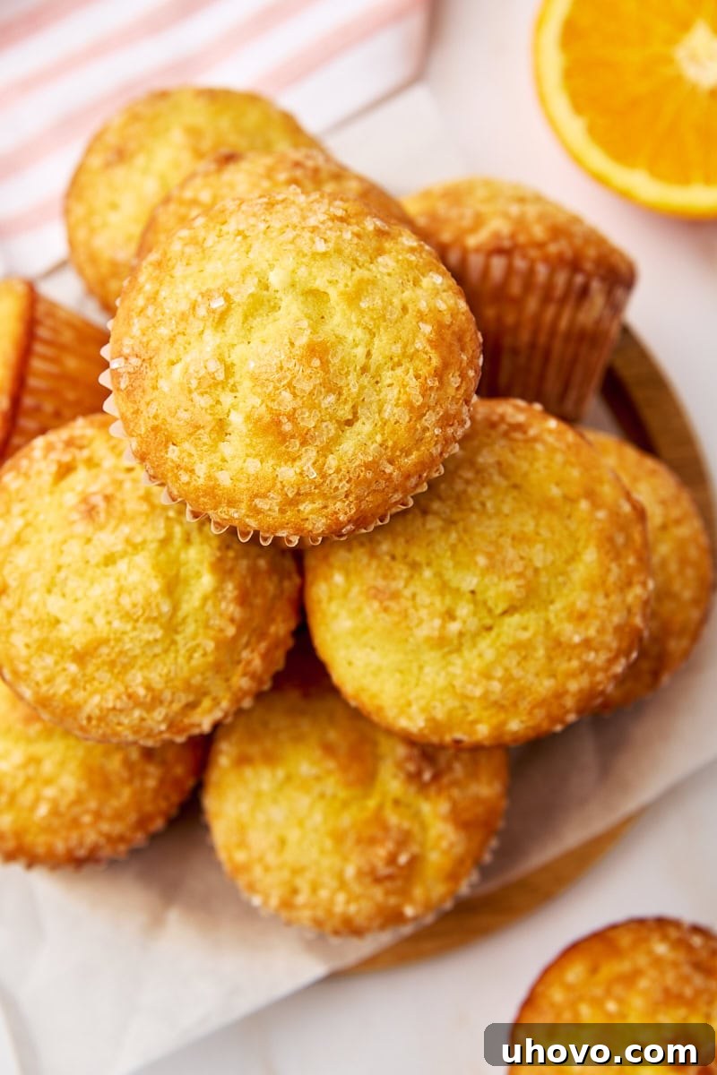 Freshly baked orange ricotta muffins stacked on a parchment-covered wooden plate, showcasing their golden tops and tender texture
