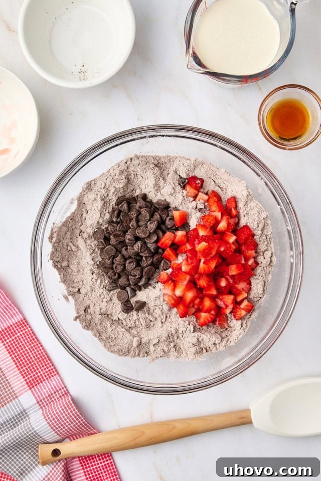 Overhead view of chopped fresh strawberries and chocolate chips folded into the scone dough mixture.