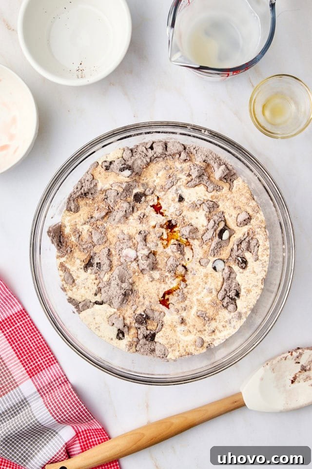 Overhead view of heavy cream and vanilla extract being added to the scone dough in a bowl.