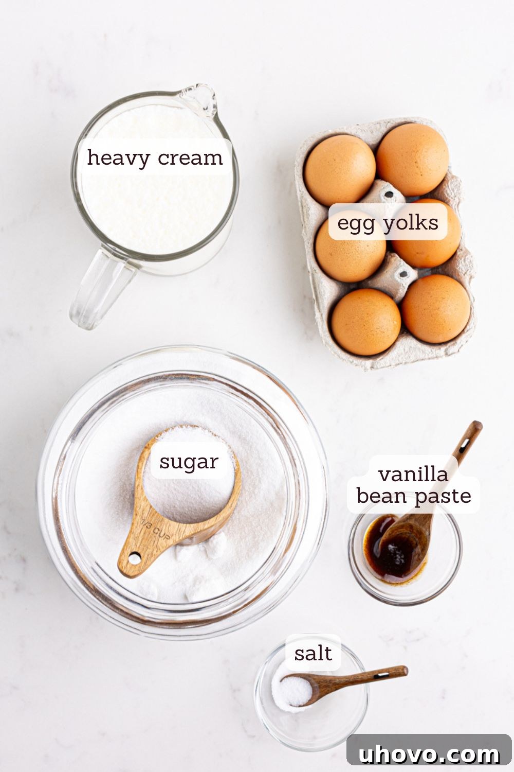 An overhead view showcasing all the simple yet essential ingredients laid out for making crème brûlée, including eggs, sugar, cream, and vanilla bean paste.